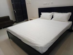 a large white bed with white sheets and pillows at ComfortWings in Coimbatore +10 photos