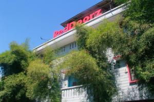 a white building with a red neon sign on it at RedDoorz @ Sersan Bajuri in Bandung