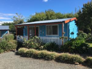une petite maison bleue dans un jardin dans l'établissement Boat Harbour Garden Cottages, à Boat Harbour
