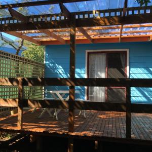 a deck with a pergola in front of a blue house at Boat Harbour Garden Cottages in Boat Harbour