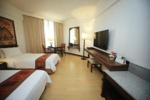 a hotel room with two beds and a flat screen tv at Wiang Inn Hotel in Chiang Rai