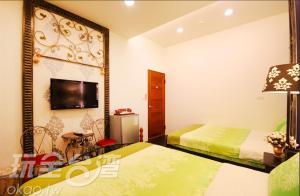 1 dormitorio con 2 camas y TV en la pared en Dream House B&B en Luodong