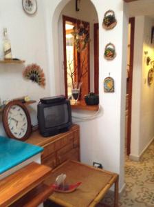 a room with a tv and a table and a clock at Residence Vulcano Cottage in Vulcano