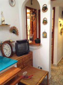 a room with a tv and a table and a clock at Residence Vulcano Cottage in Vulcano