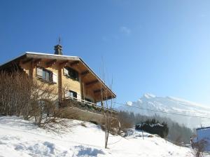 un edificio en la nieve con una cruz. en Chambre d'Hôtes La Trace, en La Clusaz