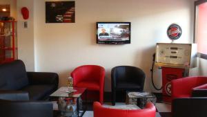 a waiting room with red chairs and a tv on the wall at Enzo Hôtels Pont-à-Mousson BY Kyriad Direct in Pont-à-Mousson
