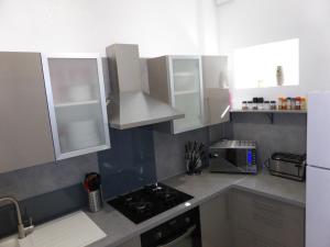 a kitchen with white cabinets and a sink and a microwave at Appartement Bayeux in Bayeux