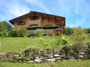 una casa en una colina con flores delante en Chambre d'Hôtes La Trace, en La Clusaz