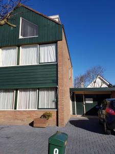 a green building with a car parked in front of it at Logies De Sering Texel in De Koog