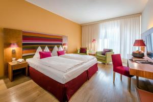 una camera d'albergo con un grande letto e una scrivania di Hotel Therme Meran - Terme Merano a Merano