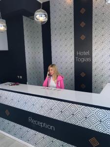 a woman talking on a cell phone at a reception desk at Togias Hotel in Aegina Town