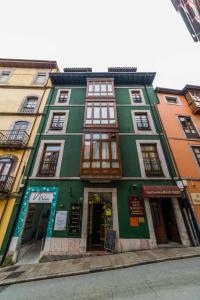 a green building with windows on a street at Apartamentos San Roque in Llanes