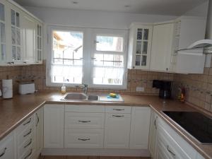 a kitchen with white cabinets and a sink and a window at Ferienhaus in der Sonne in Bad Hindelang