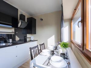 a dining room with a white table and a kitchen at VacationClub - Sand Hotel Apartment 308 in Kołobrzeg