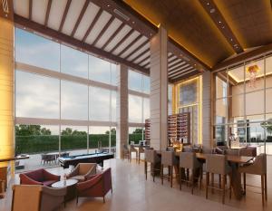 a restaurant with tables and chairs and large windows at Mercure Chennai Sriperumbudur in Sriperumbudur