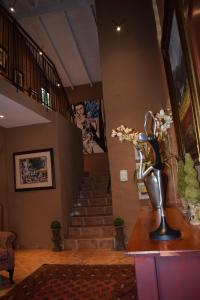 a lobby with a staircase and a vase of flowers on a table at Chateau Vue in Pretoria