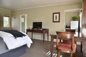 a bedroom with a desk and a bed and a table and chair at Bradleys Garden Bed and Breakfast in Taumarunui