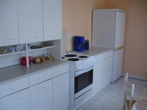 La cuisine est équipée de placards blancs et d'un four avec plaques de cuisson blanches. dans l'établissement Ferienwohnung Schob, à Dyrotz