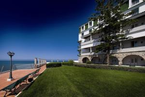a park bench next to a building next to the ocean at Vila Gale Ericeira in Ericeira