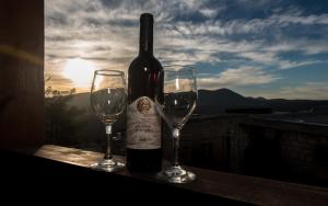 a bottle of wine and two glasses on a ledge at Myrtle the Turtle Guesthouse in Safed