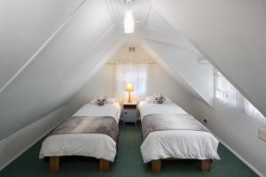 three beds in a attic room with a window at Stone Chimney Cottage in Hermanus