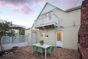 a house with a balcony and a table and chairs at Stone Chimney Cottage in Hermanus
