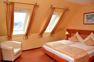 ein Schlafzimmer mit einem Bett und einem Stuhl sowie zwei Fenstern in der Unterkunft Gasthaus Zur Rebe in Mehring