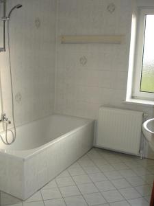 La salle de bains blanche est pourvue d'une baignoire et d'un lavabo. dans l'établissement Ferienwohnung Schob, à Dyrotz