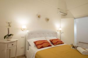 a white bedroom with a bed with two orange pillows at Palazzo Rattazzi in Monopoli