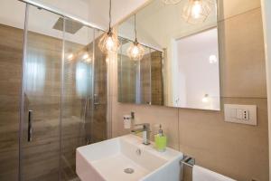 uma casa de banho com um lavatório, um chuveiro e um espelho. em Palazzo Rattazzi em Monopoli