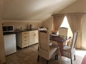 プレトリアにあるChateau Vue Guesthouseのキッチン(テーブル、椅子、電子レンジ付)