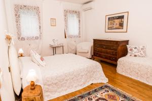 a white bedroom with two beds and a dresser at Agriturismo Alba in Baone