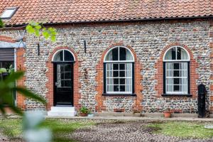 a brick building with three windows and a door at The Grove Cromer in Cromer