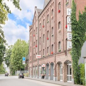 un gran edificio de ladrillo rojo con un cartel. en Hotel Dampfmühle, en Neukirchen-Vluyn