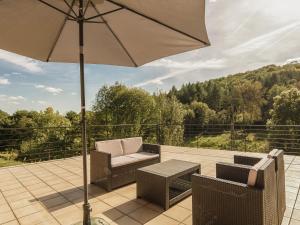 eine Terrasse mit einem Sonnenschirm, Stühlen und einem Tisch in der Unterkunft Modern Villa in S rilhac with Private Pool in Beynat