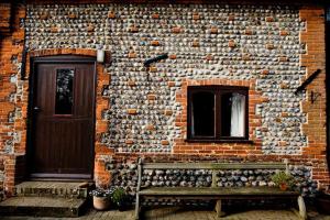 a brick building with a wooden door and a bench at The Grove Cromer in Cromer