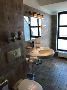 een badkamer met 2 wastafels, een toilet en een spiegel bij Hotel Poseidon in Bayreuth