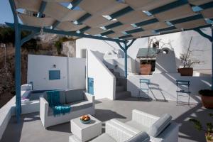 a patio with white furniture and a blue roof at Semeli Cave House in Pyrgos