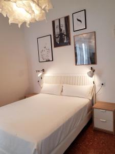 una camera da letto con un letto bianco e quadri appesi al muro di Las Atarazanas - Design Hostal a Siviglia
