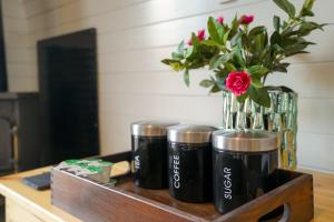 a group of three coffee cups on a table with a vase of flowers at Deluxe Glamping Pod with Hot Tub in Frodsham