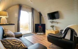 a living room with a couch and a tv at Deluxe Glamping Pod with Hot Tub in Frodsham