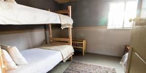 a bedroom with two bunk beds and a window at Volmoed Cottage in Oudtshoorn