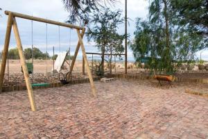a swing set in a playground with the ocean in the background at Volmoed Cottage in Oudtshoorn