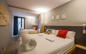 a bedroom with two beds with white sheets and red pillows at Yeah Barcelona Hostel in Barcelona