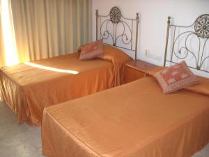トレモリノスにあるCASTILLO DE SANTA CLARA 2のオレンジのシーツが備わるベッド2台(1室あたり)