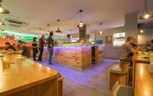 a group of people standing around a bar in a restaurant at Yeah Barcelona Hostel in Barcelona