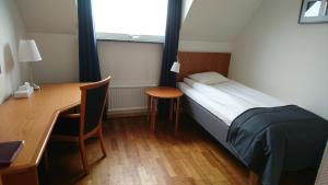 Schlafzimmer mit einem Bett, einem Schreibtisch und einem Tisch in der Unterkunft Haga Värdshus in Hillerstorp