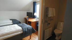 a bedroom with a bed and a desk with a computer at Haga Värdshus in Hillerstorp
