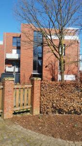 a brick building with a fence and a tree at Refugium 1 in Emsdetten