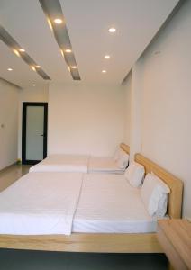 two beds in a room with white walls at Khoi Nguon in Da Nang